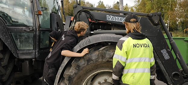 Kuva, jossa opiskelijat huoltavat traktoria.